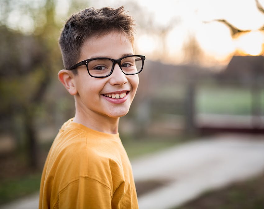 kid in glasses smiling over his shoulder