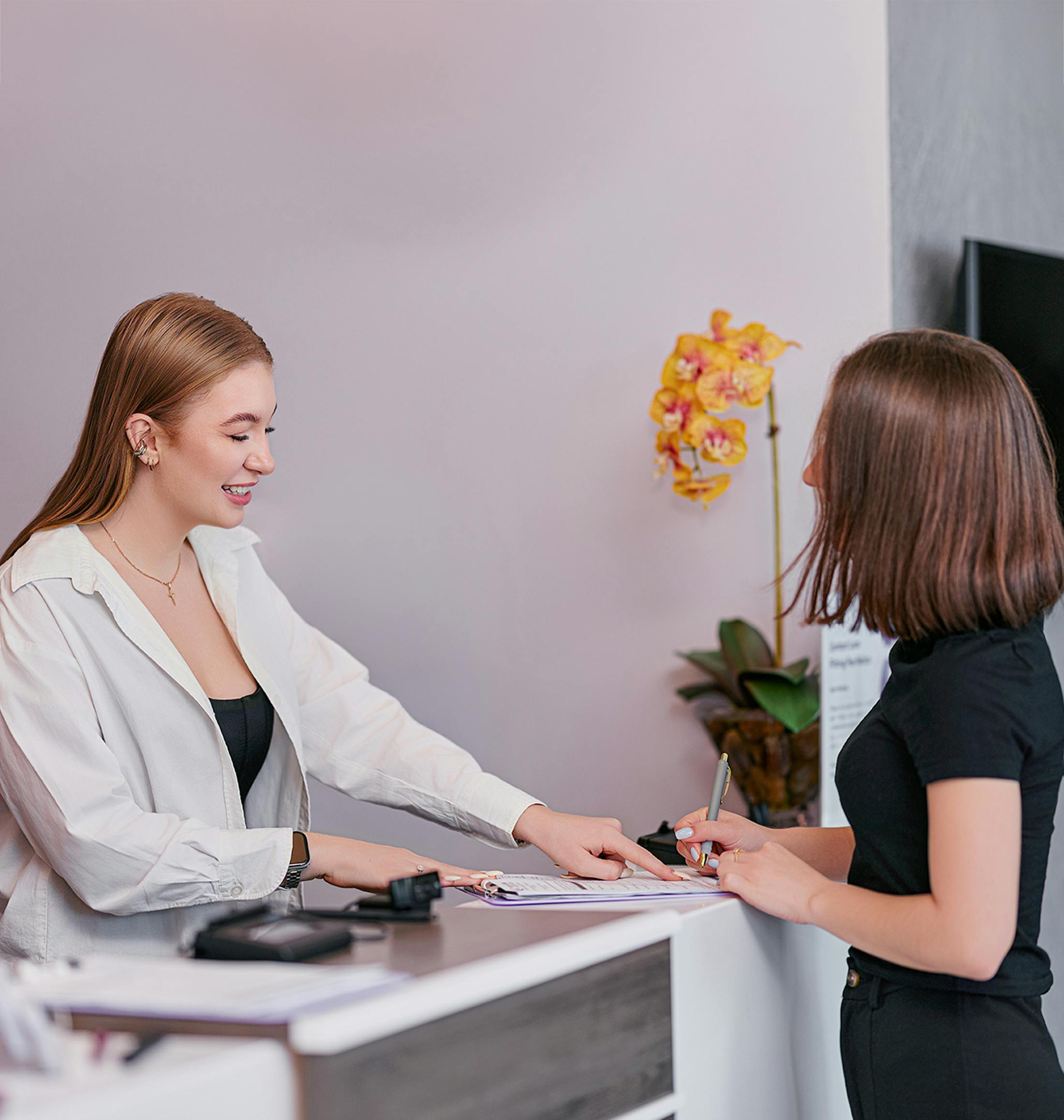 receptionist pointing to paperwork for a patient