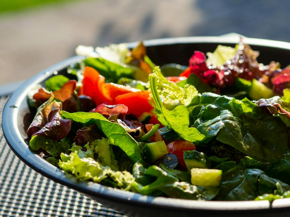 A mixed green salad with tomatoes and cucumber