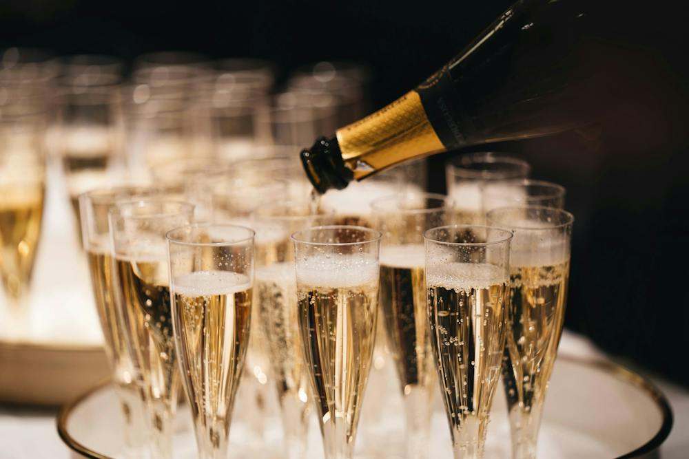 Champagne being poured into a row of flutes