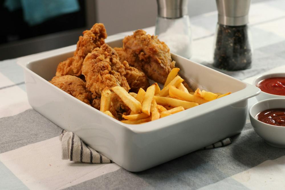 Chicken tenders and french fries in a white dish, with ketchup on the side