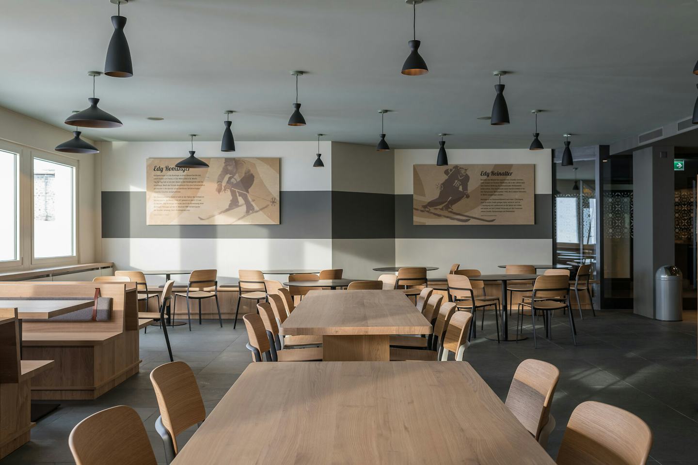 Free-Flow-Restaurant Edy’s in der Bergstation Corviglia St. Moritz. Alles sehr schlicht gehalten, setzten die Holzstühle und Tische auf Funktionalität ohne grosse Dekorationen im Raum. An der Wand hängen zwei Bilder von Skifahrern.