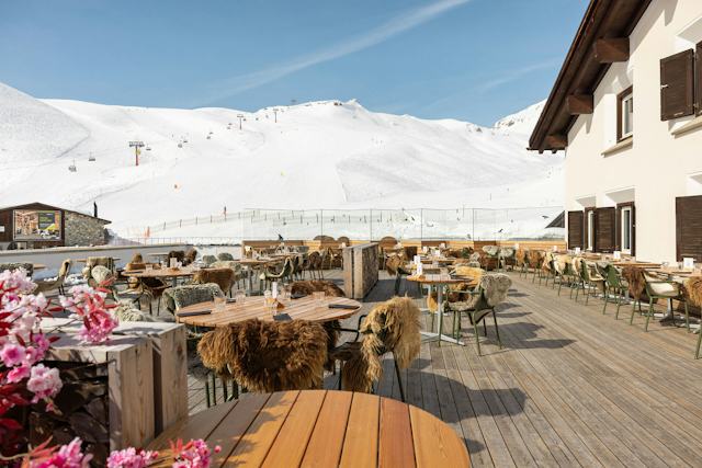 Restaurant & Bar Marguns Sonnenterrasse | Winter Aussenansicht der Sonnenterrasse des Restaurants & Bar Marguns im Skigebiet Corviglia. Zu sehen sind Sitzbereiche mit Fellen auf der Terrasse, die einen Blick auf die Skipisten von Corviglia und eine Sesselbahn bieten.