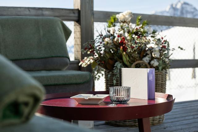 Sitzecke mit Grüner Decke auf der Sonnenterrasse des White Marmot auf Corviglia.