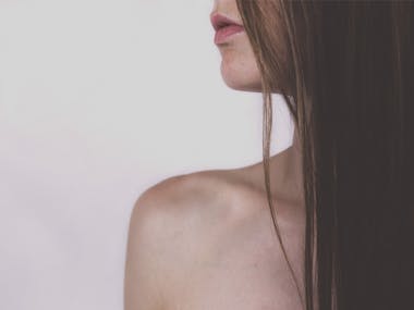 Profile of a woman with bare shoulder and long hair covering her face