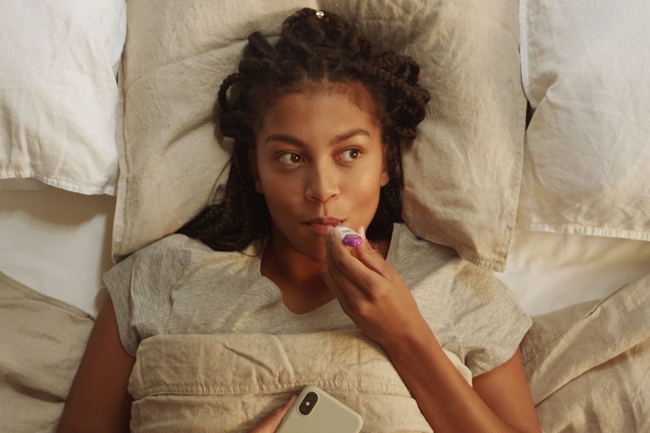 woman lying in bed measuring her temperature with a thermometer
