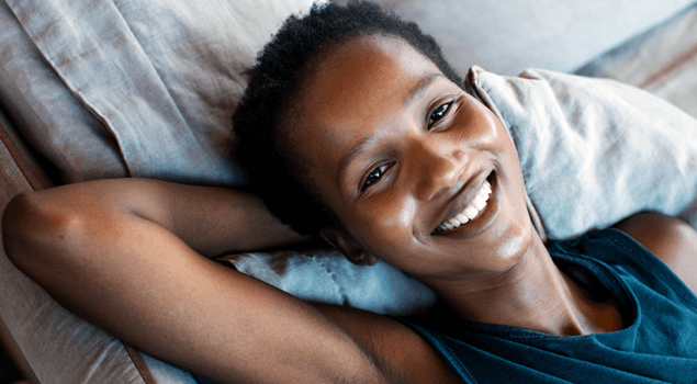 mujer acostada en la cama con una amplia sonrisa en su rostro