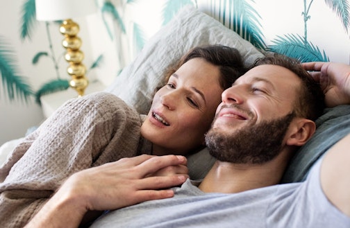 Couple holding hands and laughing in bed