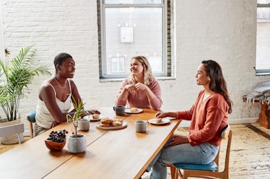 3 Women sitting round a table having coffee and talking