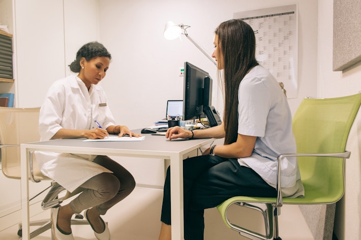 Patient sitting down talking with a medical proffessional in a doctors office