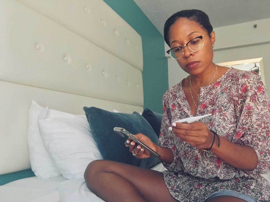 Latricia looking at phone and Natural Cycles thermometer