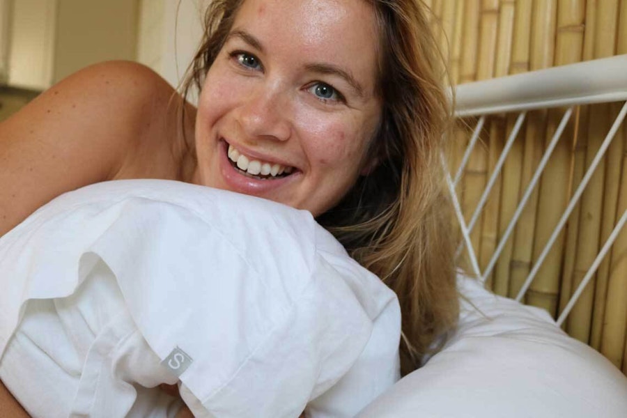 Joanna lying in bed, holding a pillow 