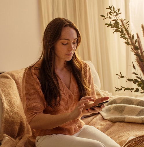 Woman using her phone while seating on a couch.