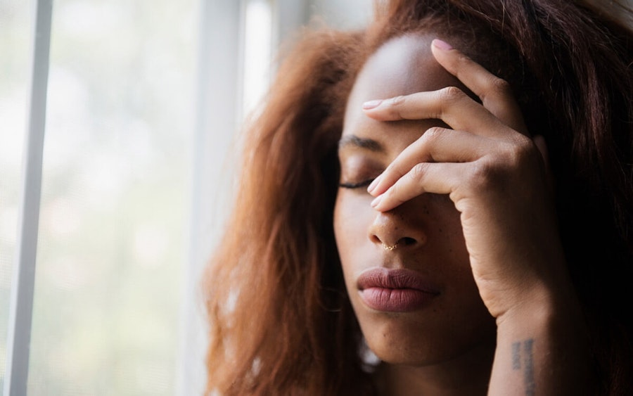 Woman with her hand to her forehead looking in pain or stressed