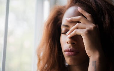 Woman with her hand to her forehead looking in pain or stressed