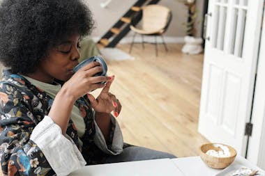 Woman sat at table drinking from blue mug