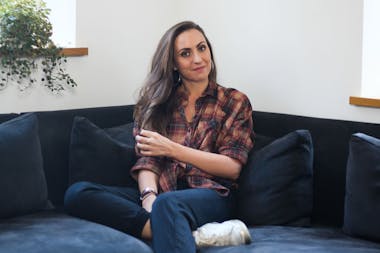 Zoƫ sat on corner sofa looking at the camera