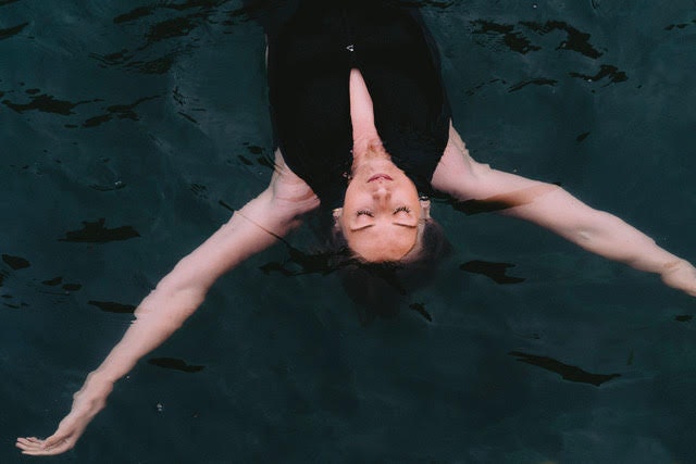 Photo of Alice floating on her back in dark water looking relaxed