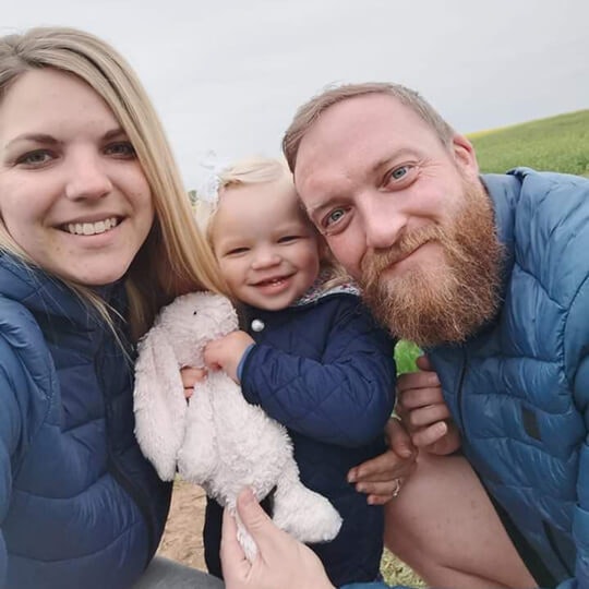 Proud parents Charlotte & Mark outside with adorable baby Pippa and her rabbit doll