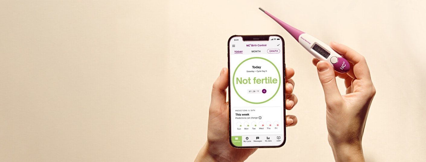 Hands holding a mobile phone with the Natural Cycles app and a thermometer