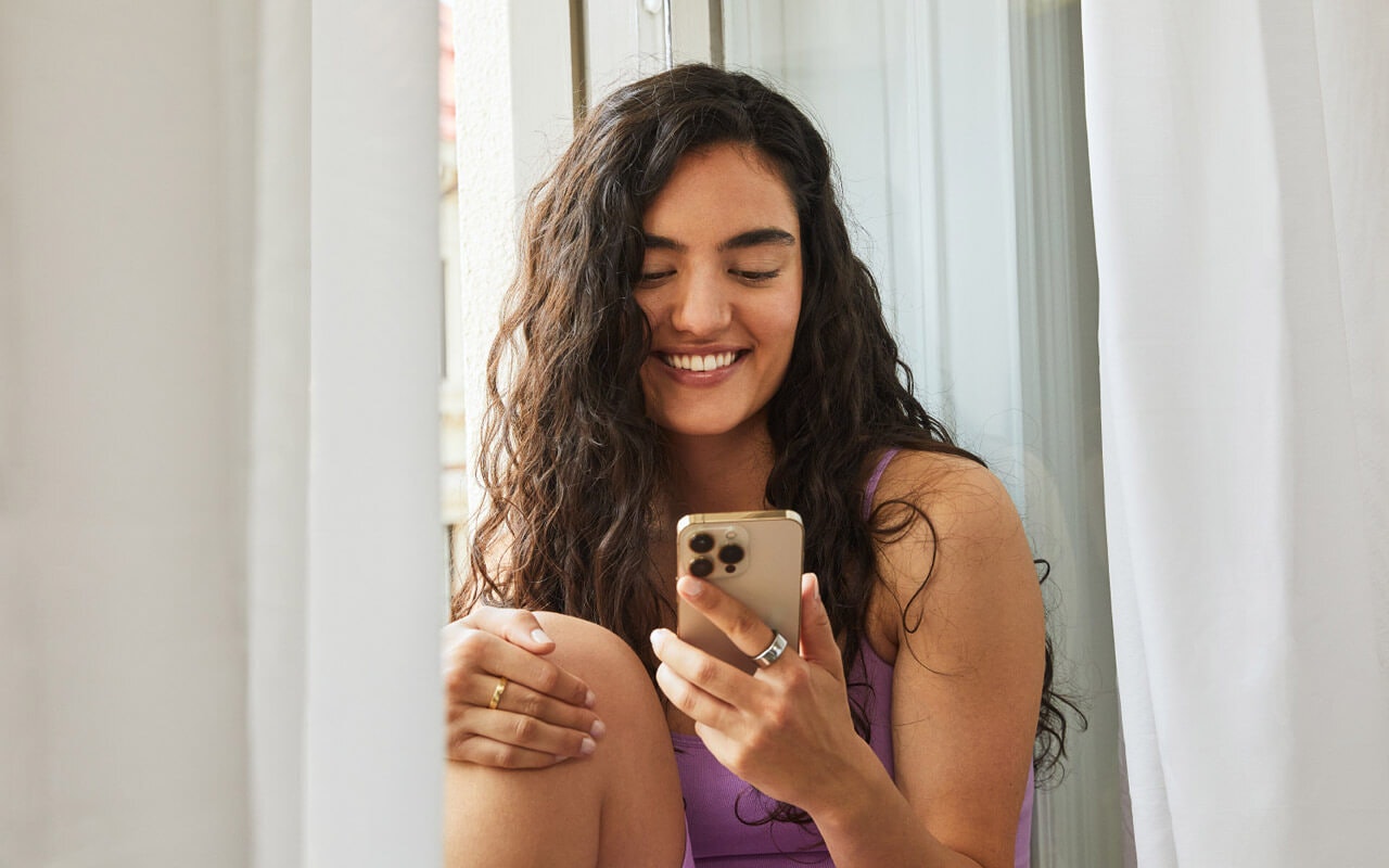 Woman holding Natural Cycles app while wearing Oura ring