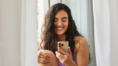 Smiling woman looking at phone wearing Oura Ring