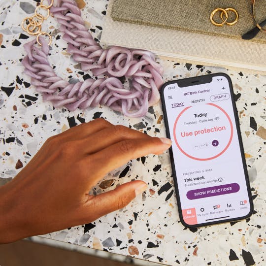 Hand over phone and Natural Cycles app on display