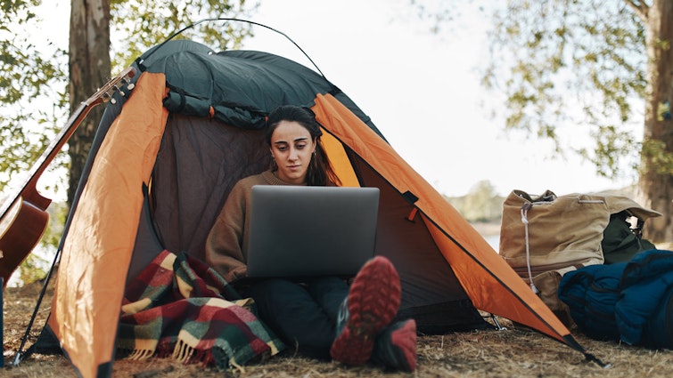 Woman sitting in her tent on a laptop