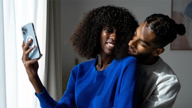 Couple cuddling while holding up a phone