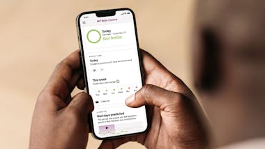 hands holding phone showing Natural Cycles' Partner View fertility status