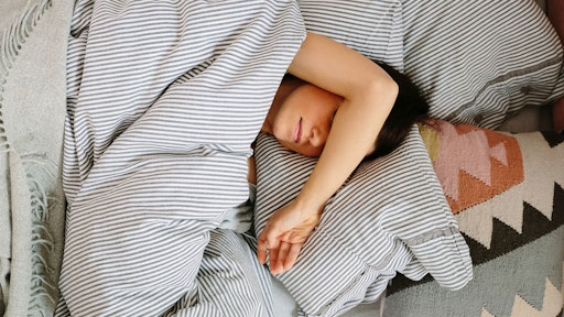 Woman in bed with her arm over her face