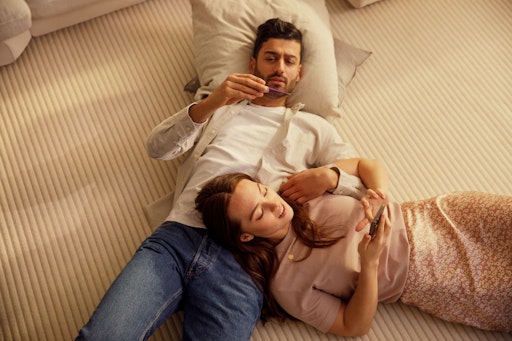 Couple lying on the floor, man looking at thermometer