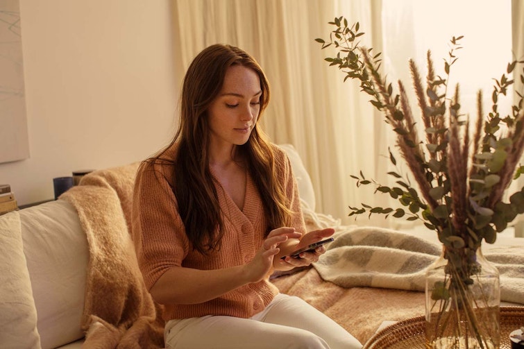 Woman sat on the couch looking at her phone