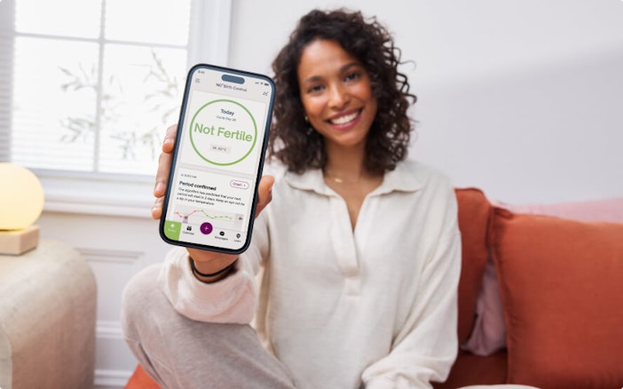 Woman holding up Natural Cycles app