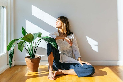 woman sat on the floor with her face towards the sunlight