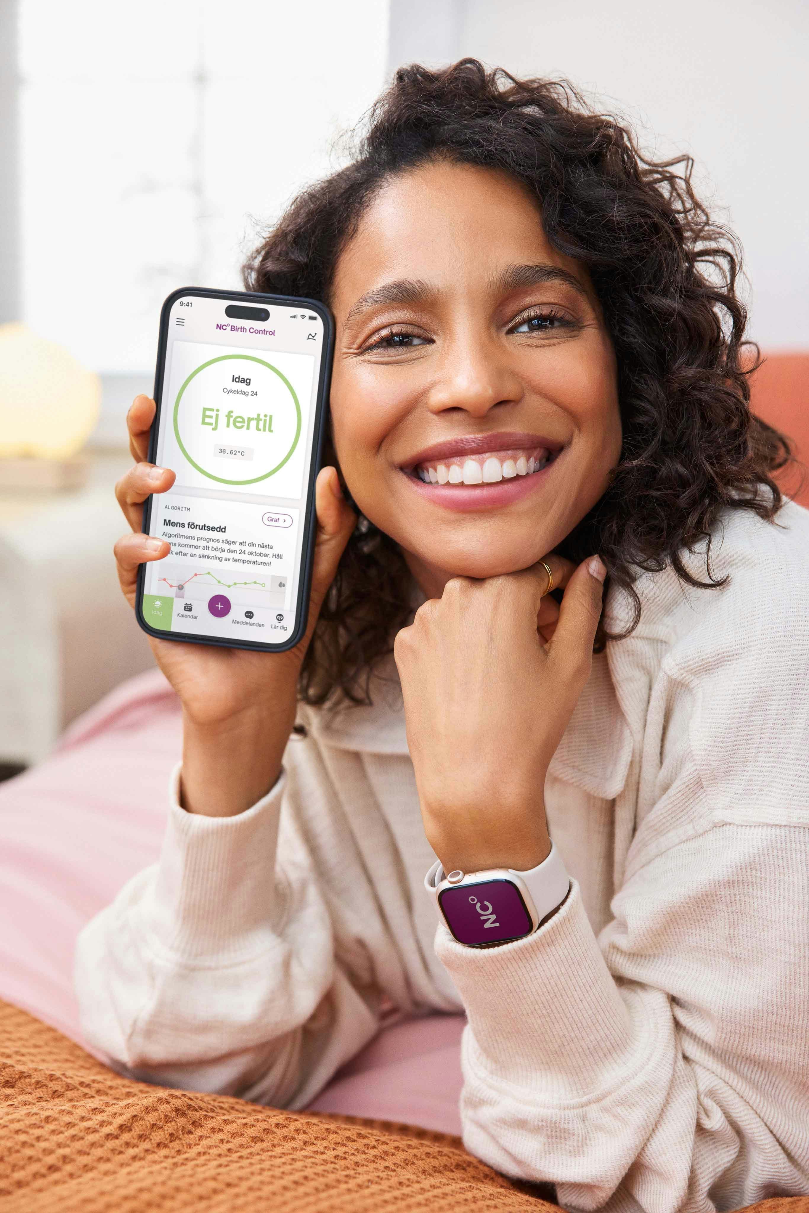 Glad kvinna håller en mobil med en ej fertil skärm och en Apple Watch på handleden