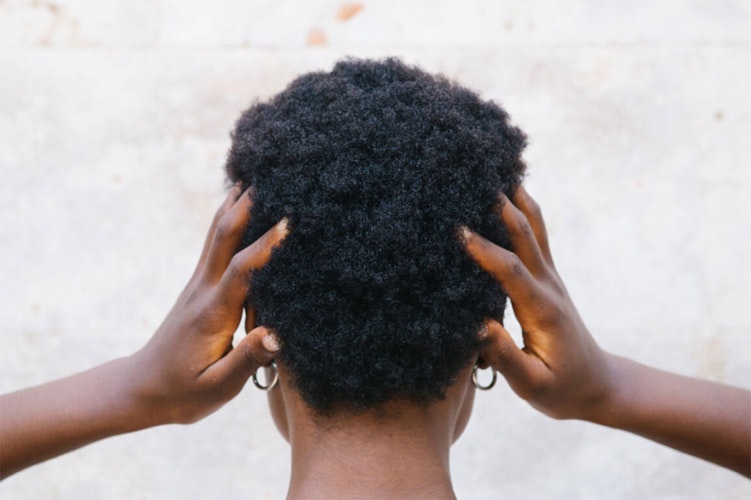 Person facing away from the camera with their hands up against their head