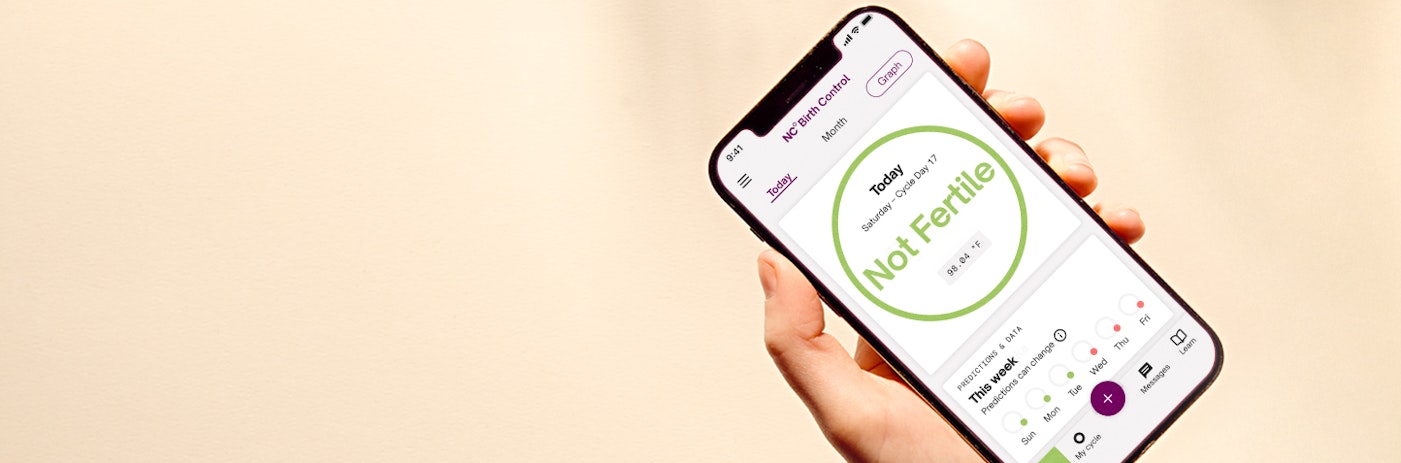 Hand holding phone with NaturalCycles app on screen