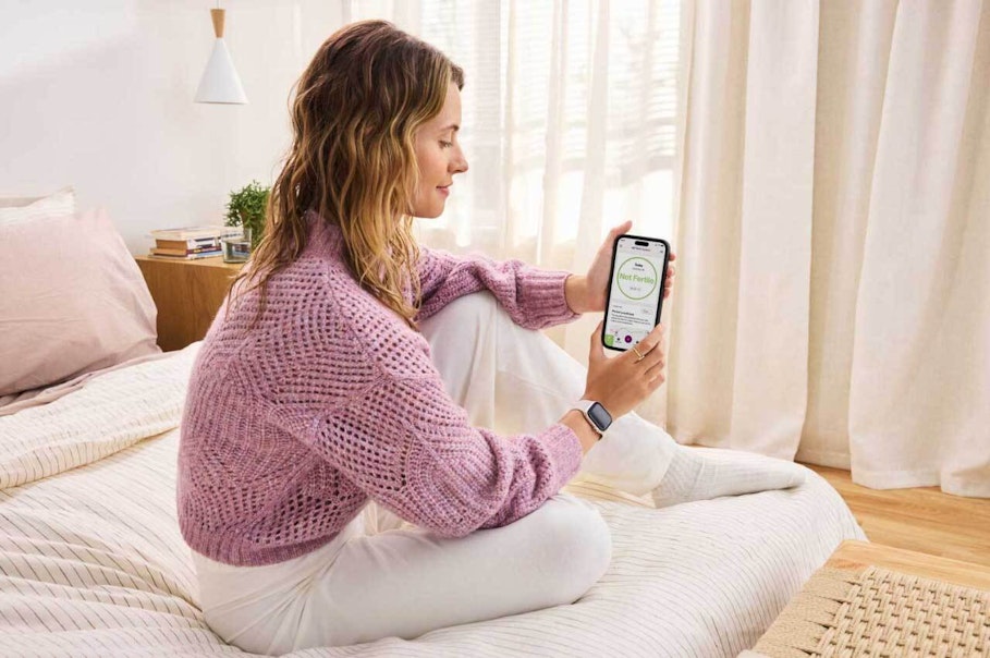 Woman sat on bed holding phone