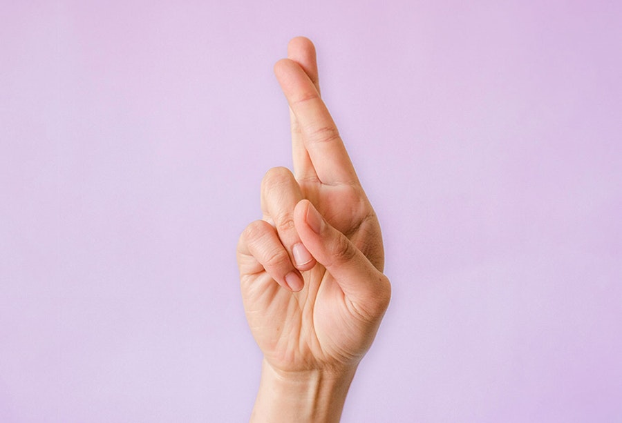 Image of a hand with crossed fingers on a lilac background