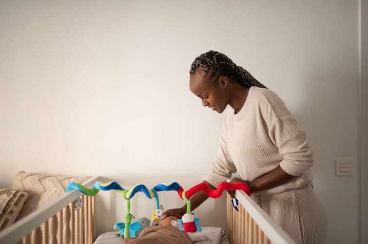 Woman standing over baby in crib