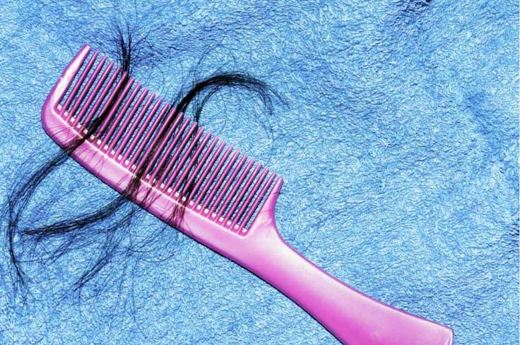 Pink comb on a blue blanket with some strands of black hair