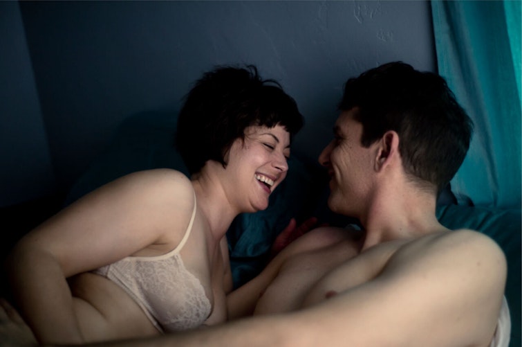 Semi--dressed couple laughing in bed together
