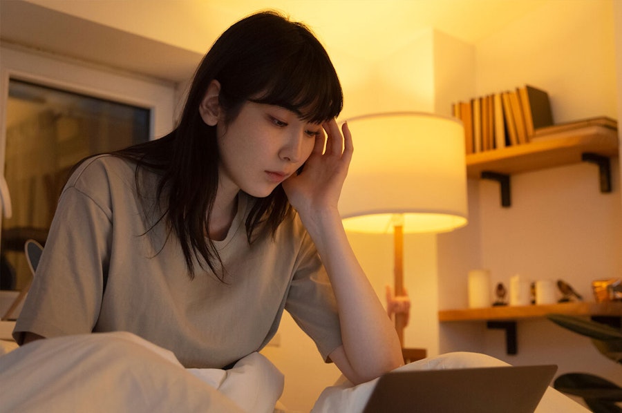 Woman with her hand to her head reading on her laptop