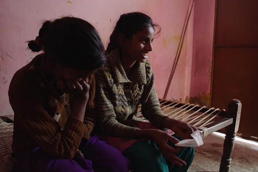 Two women smiling, holding a period pad