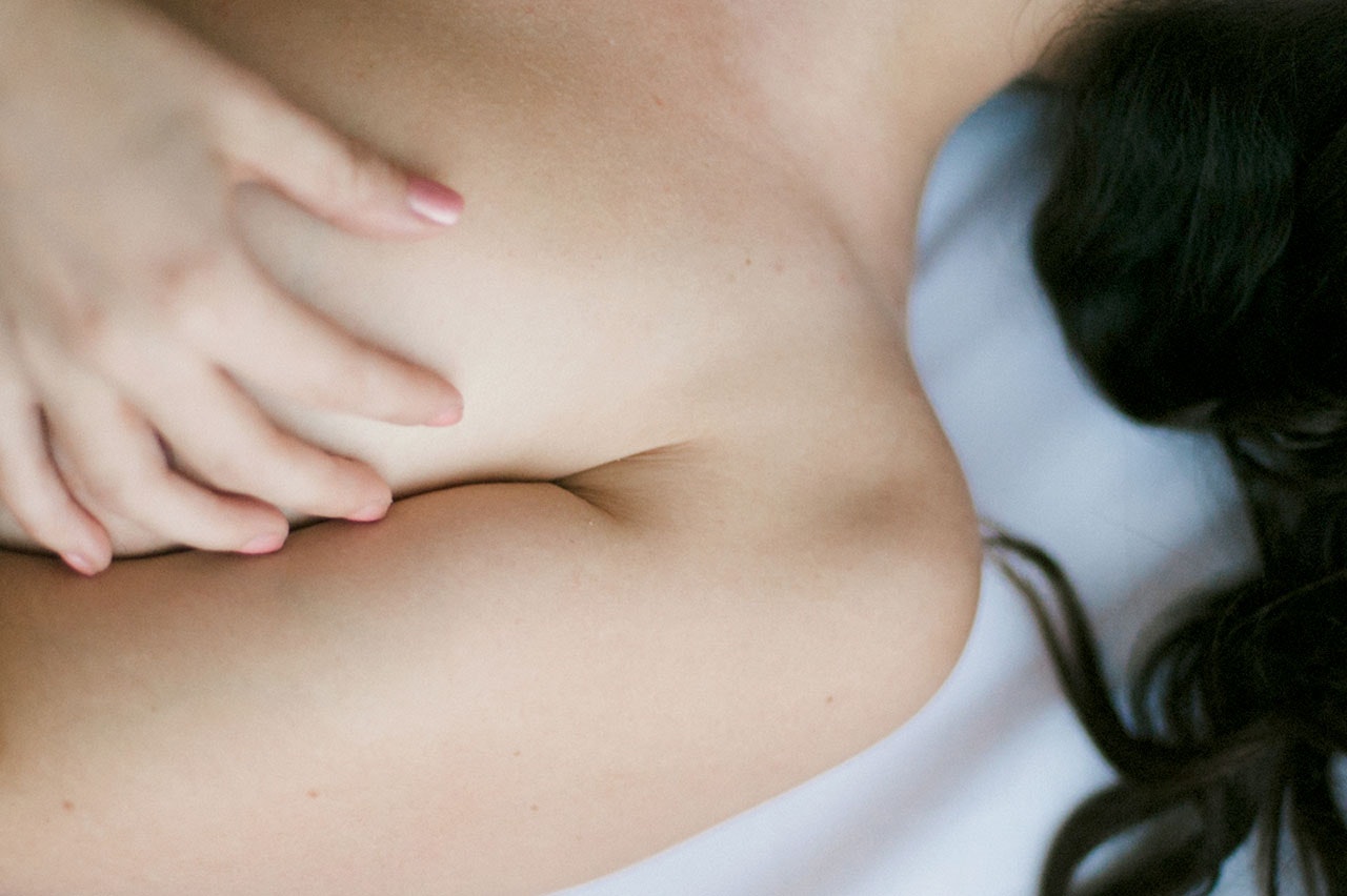 Woman lying on her back with one hand on a her breast