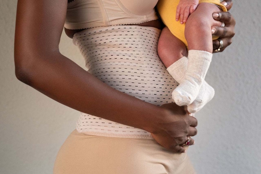 Mother holding baby wearing a postpartum belly binding