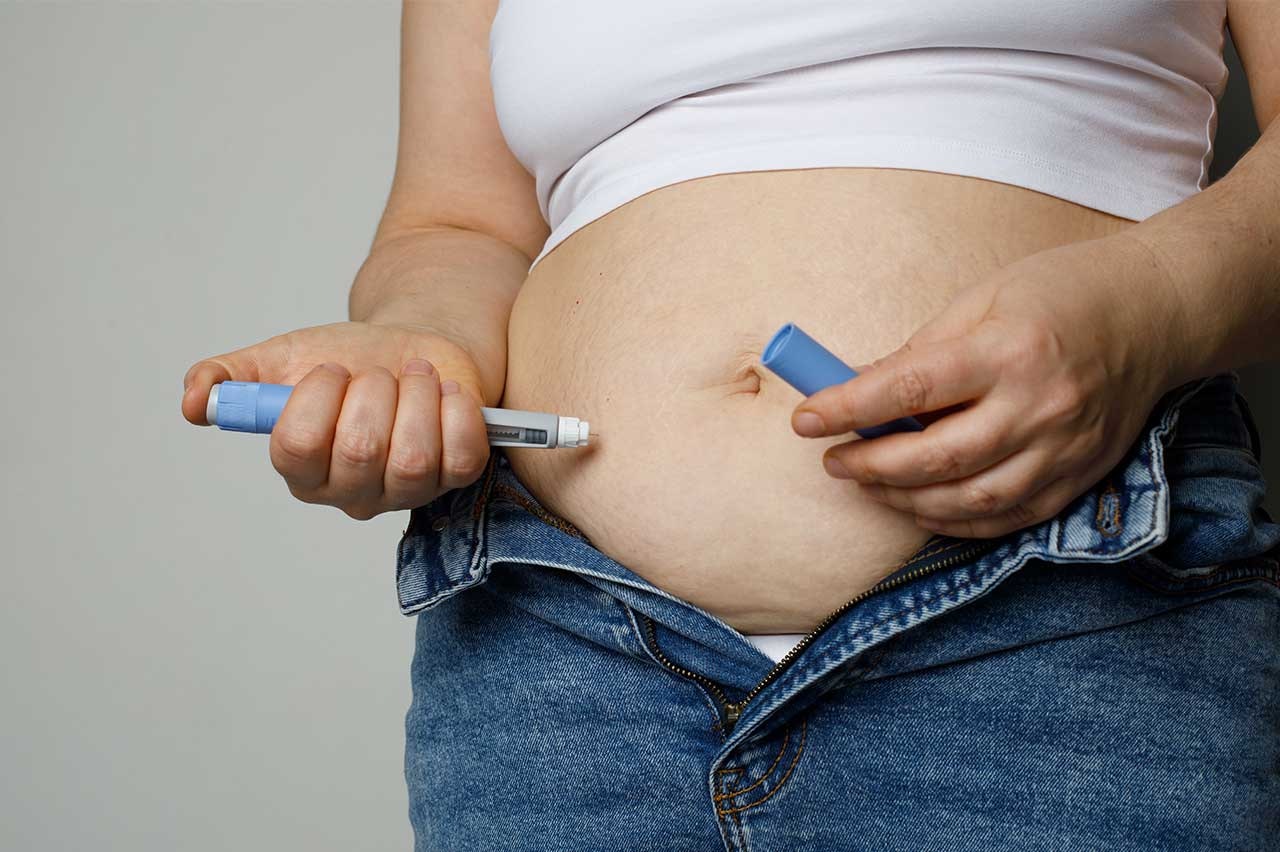Photo of a woman injecting weight-loss medication into her belly