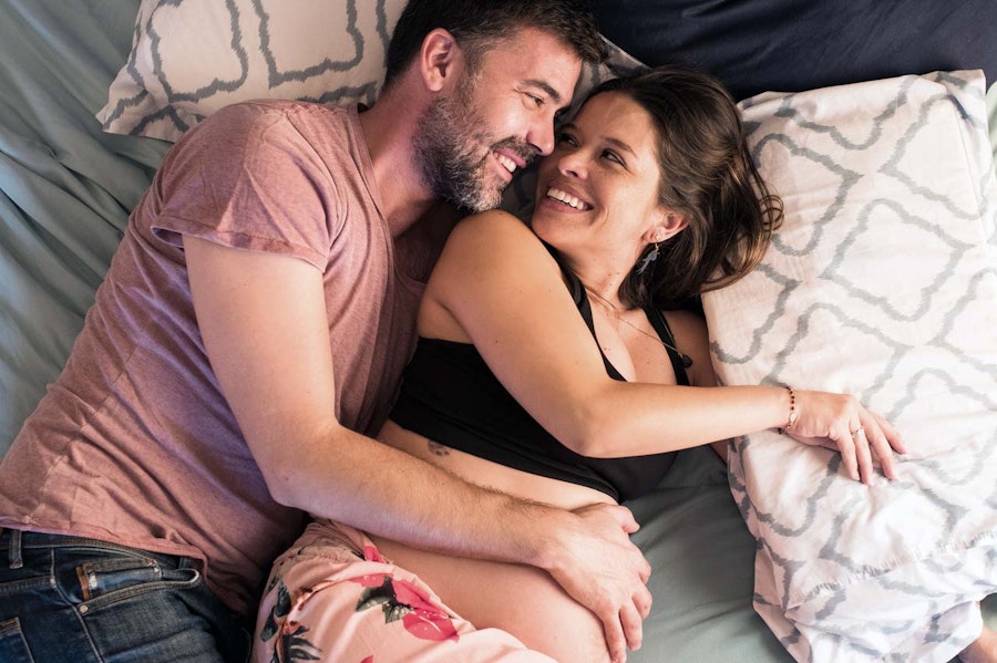 Pregnant couple cuddling on bed
