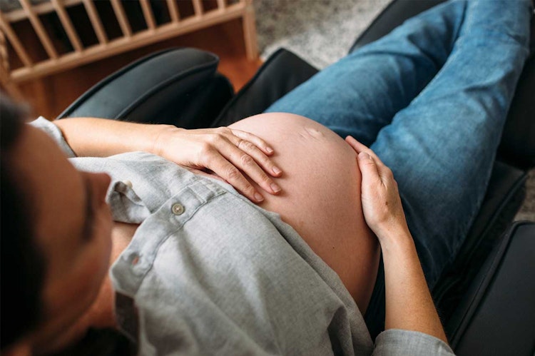 Woman sitting in a chair with one hand on her pregnant belly